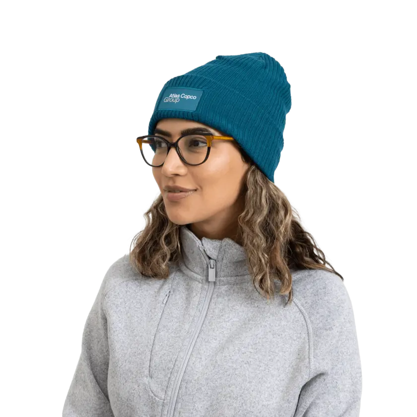 woman wearing teal winter hat with atlas copco group logo