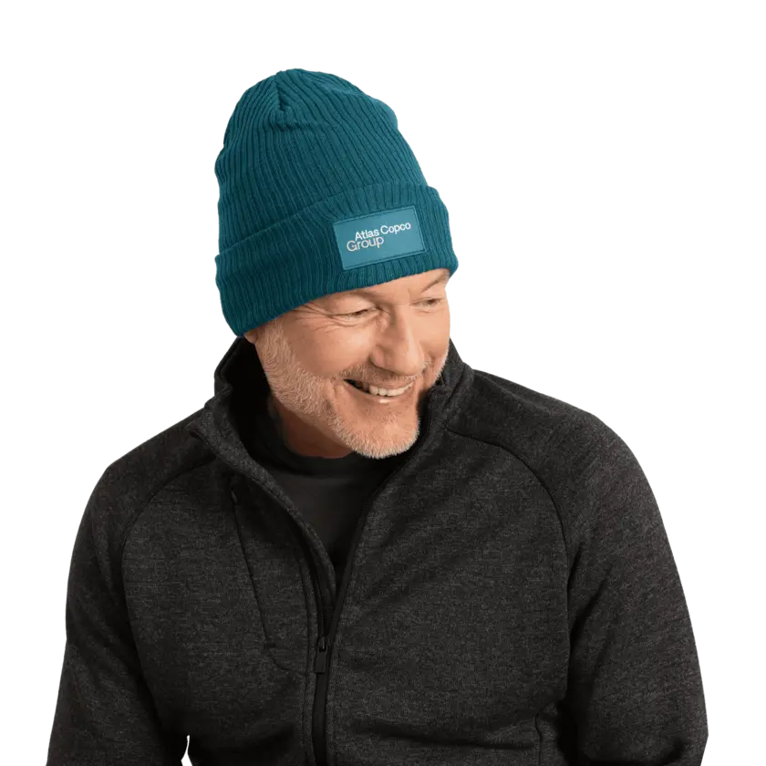 man wearing teal winter hat with atlas copco group logo